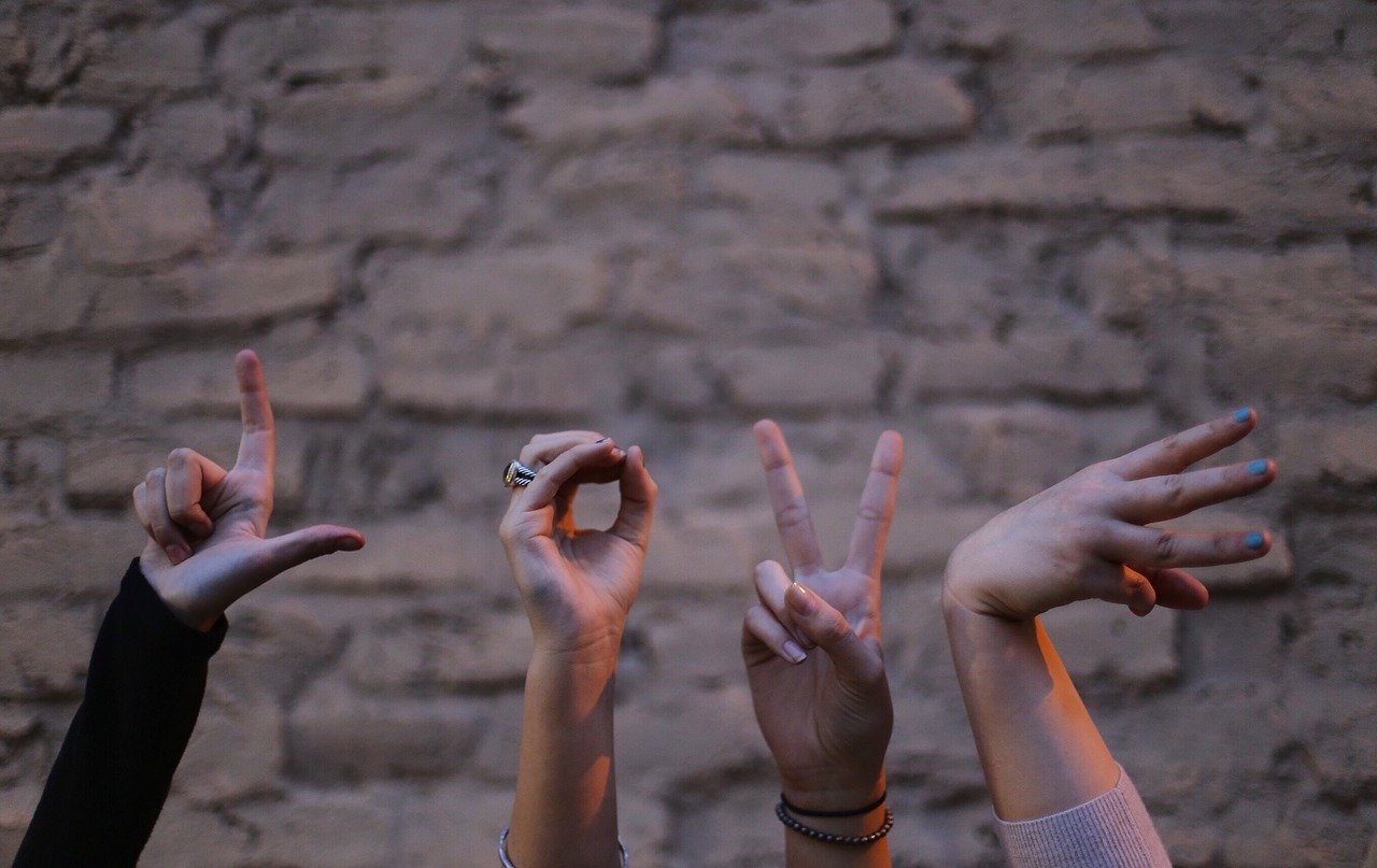 Hands reaching out through gaps in a stone wall