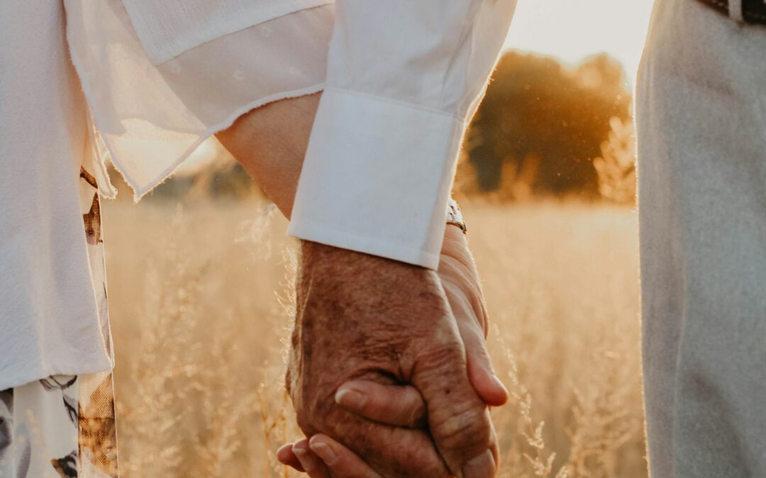 An older couple holding hands in a golden field