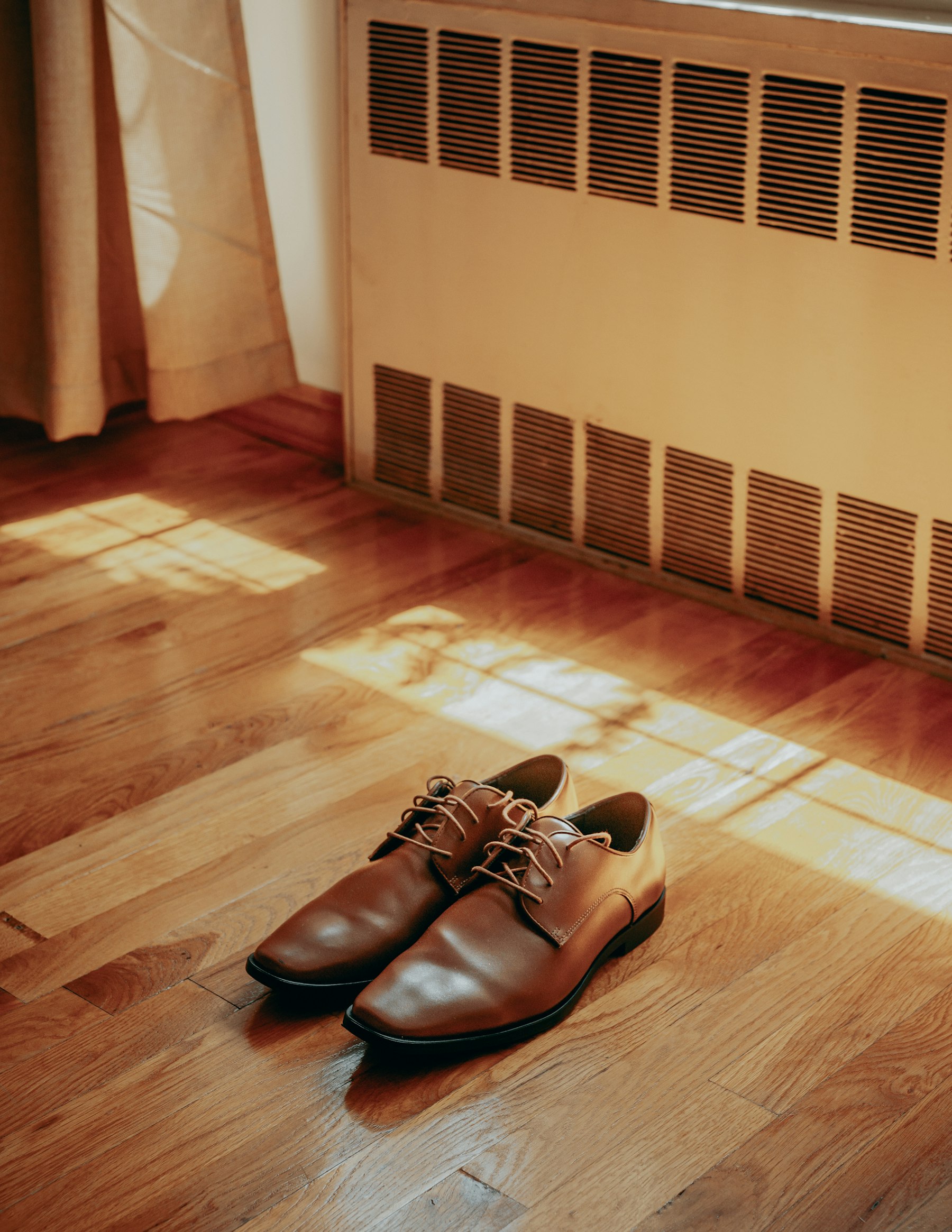 A pair of shoes left on a wooden floor in afternoon sunlight