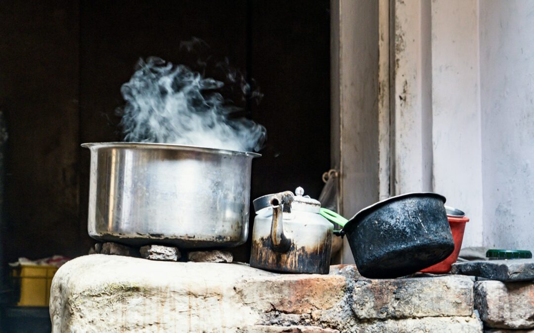 Steam rising from a steel pot sitting on an open fire