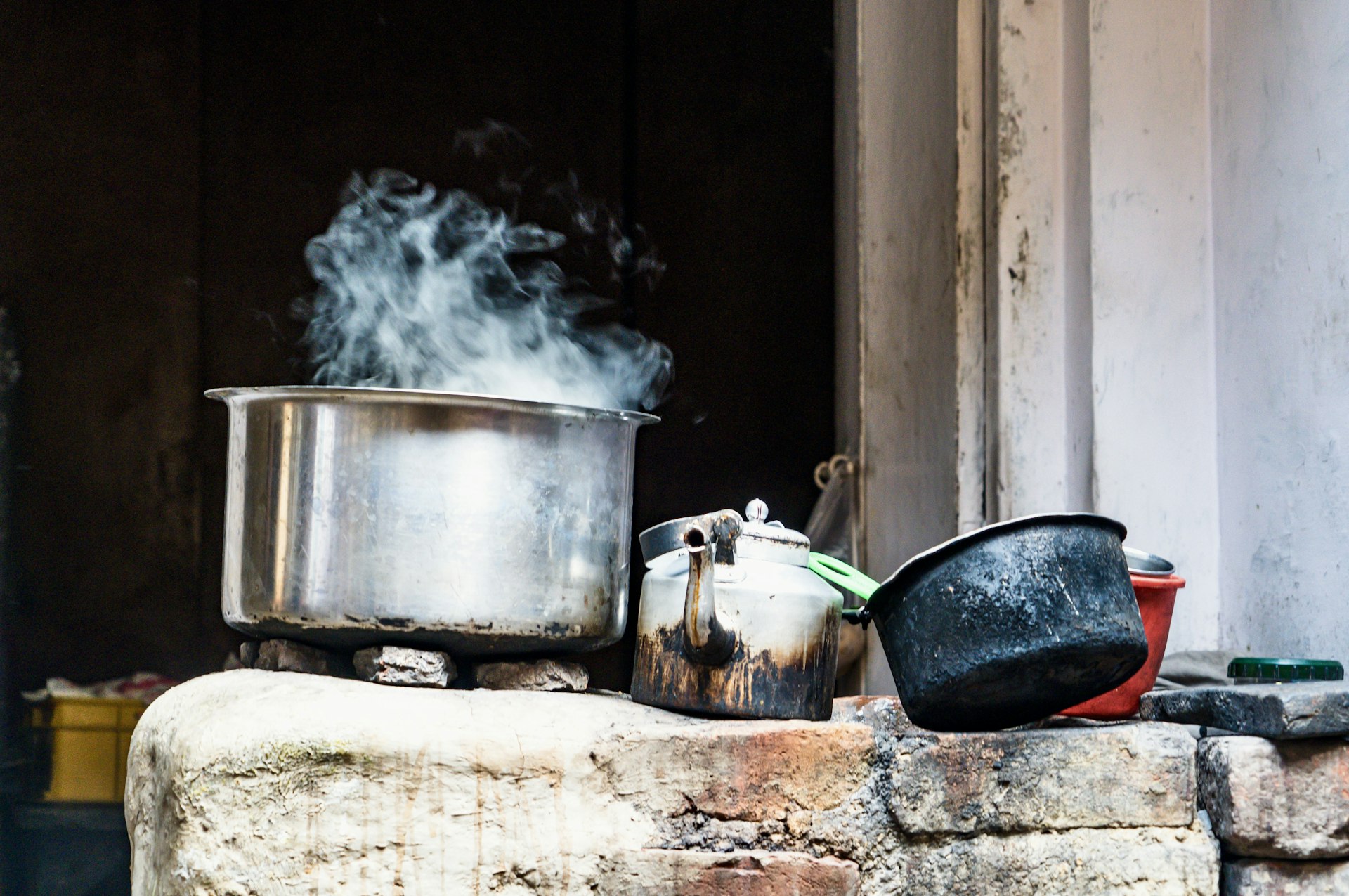 Steam rising from a steel pot sitting on an open fire